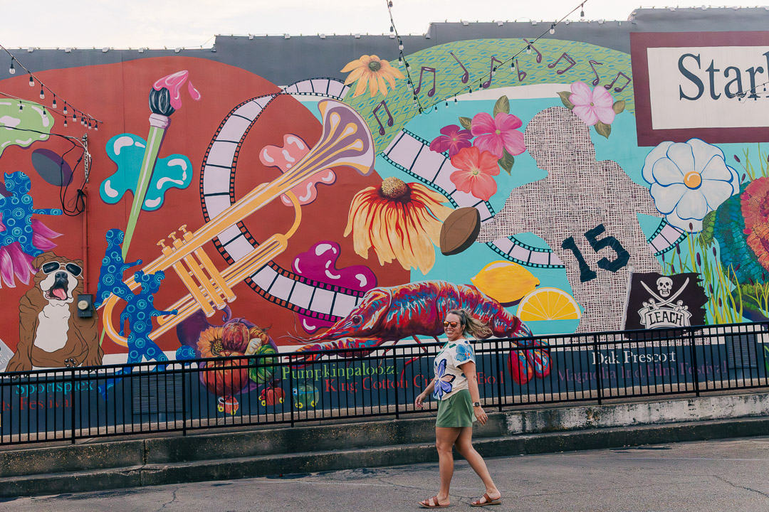 The murals in Starkville, Mississippi | a girl walking down Main Street in front of a mural