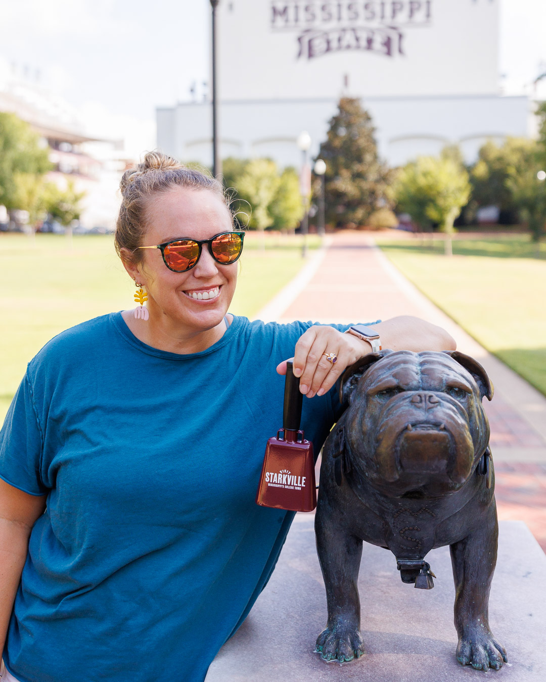 A girl with a cowbell and the bulldog statue on the Mississippi State campus