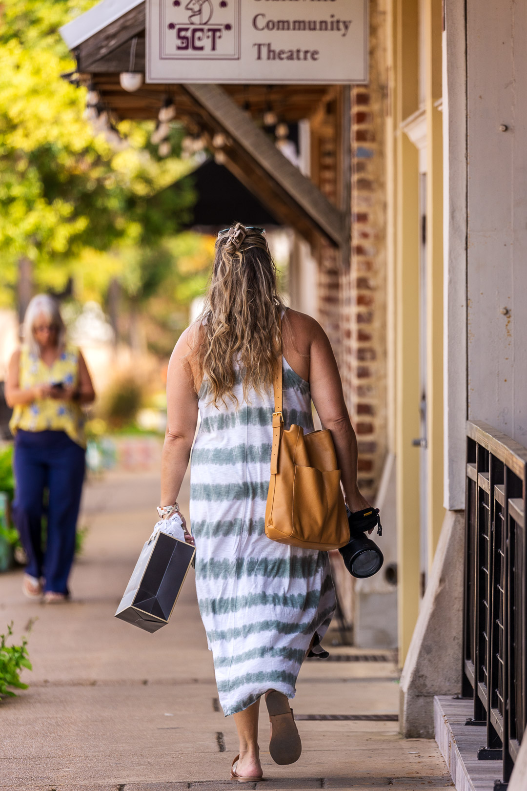 A girl strolling Starkville's Main Street district with a shopping bag in hand