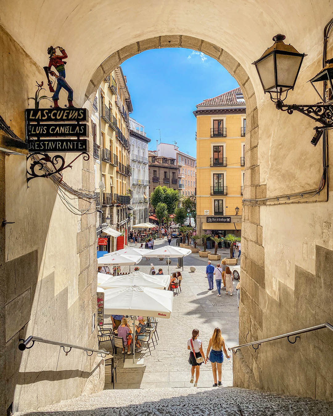 The historic Arco de Cuchilleros stone archway leading into Plaza Mayor.