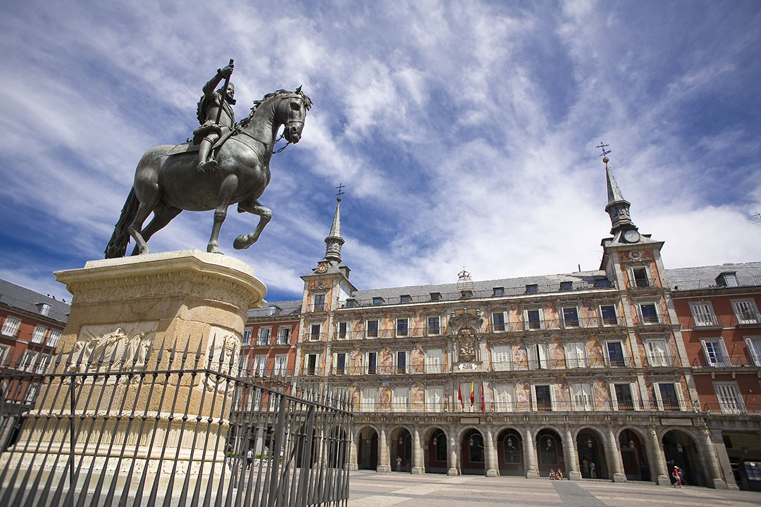The bronze equestrian statue of King Philip III in the center of Plaza Mayor, surrounded by the iconic red facades of historic Madrid.