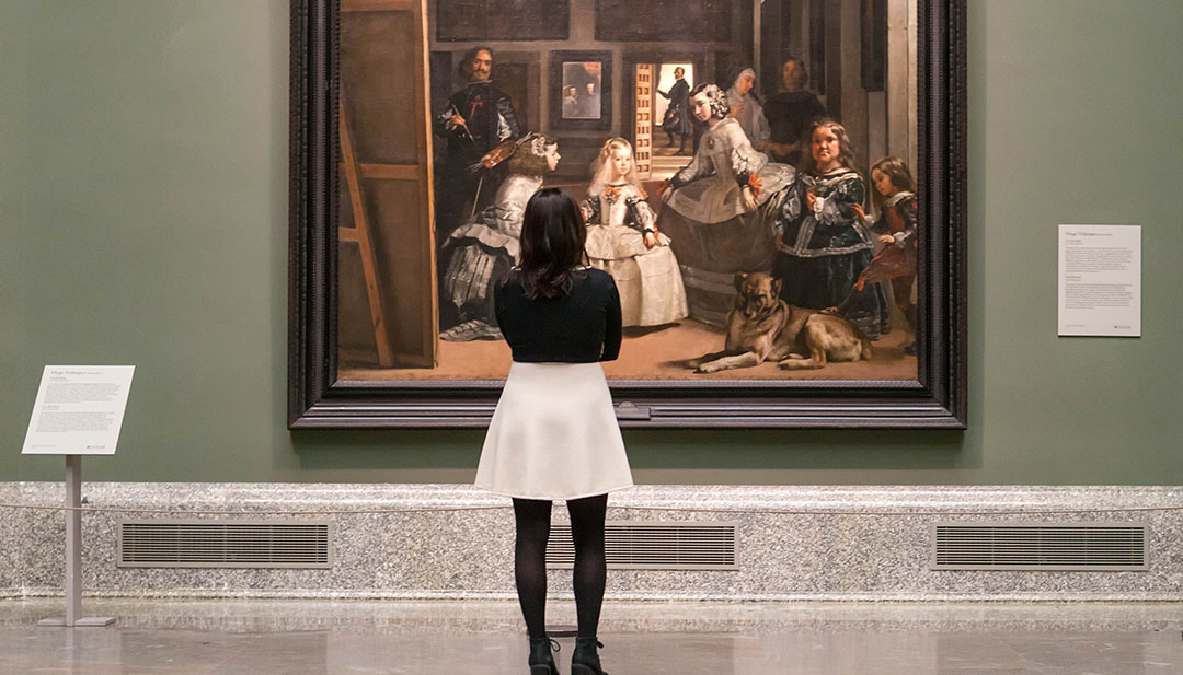 A visitor looking at famous paintings inside the Prado Museum in Madrid.