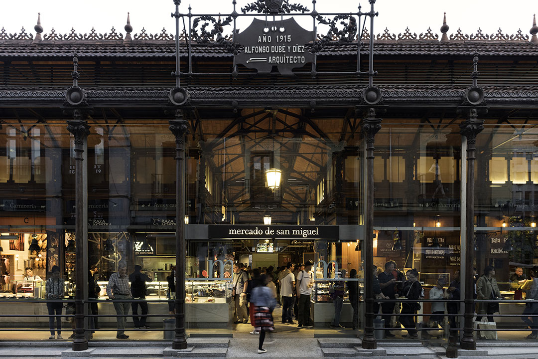 The beautiful glass and iron exterior of the Mercado de San Miguel at night.
